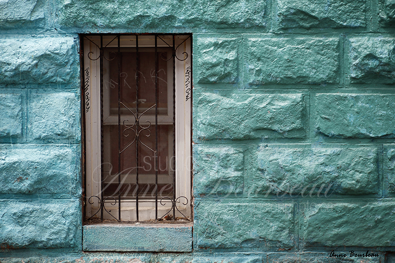 Fenêtre à barreau sur mur bleu-vert